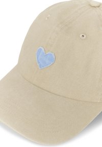 Casquette de baseball beige avec un petit cœur bleu clair brodé sur le panneau avant, fabriquée en tissu doux avec des trous de ventilation.