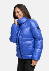 Blue puffer jacket with a shiny finish, high collar, zip closure, and front pocket. Features a quilted pattern and elastic cuffs.