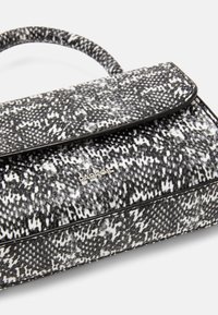 Borsa a tracolla in bianco e nero con texture a motivo serpente, dotata di chiusura a patta e manico corto intrecciato. Branding metallico visibile.