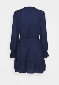 Vestido azul marino con mangas largas y abullonadas, y dobladillo con volantes. La cintura elástica crea una silueta ajustada. Tela suave y ligera con una textura sutil.