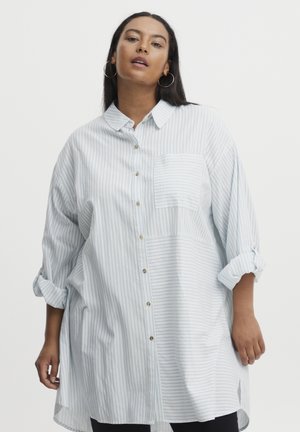 Striped button-up shirt in light blue and white, featuring a chest pocket, rolled sleeves, and a relaxed fit with a longer back hem.