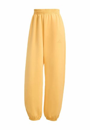 Žluté tepláky na elastický pas s manžetami na kotnících a jemně embosovaným logem na horní části stehna.