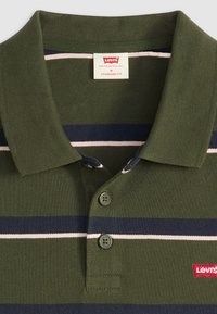 Olivovo zelená polo košeľa s námorníckymi a bielymi vodorovnými pruhmi, ktorá má dvojitý gombík, rebrovaný golier a logo Levi's na hrudi.