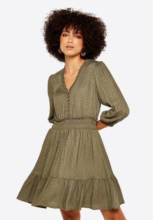 Olivgrünes Kleid mit strukturiertem Rautenmuster, V-Ausschnitt, Knopfdetails, elastischem Taillenbund und geschichteter Rockpartie. 3/4 Puffärmel.