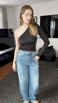 Fekete egyrészes vállú felső texturált anyagból, világoskék, magas derekú, bő szárú farmerral párosítva. Semleges színű szandálok egészítik ki a megjelenést.