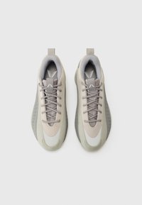 Scarpe sportive grigio chiaro realizzate in materiali mesh e sintetici. Presentano un design elegante, una superficie testurizzata e linguette per indossarle facilmente.