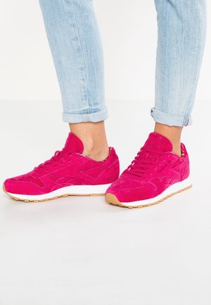 Helle pinke Wildleder-Sneaker mit strukturierten Oberflächen, weißer Zwischensohle und Gummigummisohle. Ausgestattet mit Schnürverschluss und markierten Akzenten.