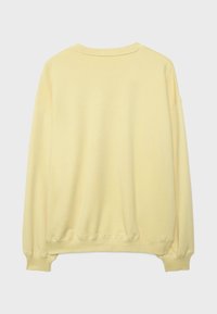 Světlé žluté crewneck tričko s dlouhými rukávy, žebrovanými manžetami a žebrovaným lemem, zobrazené zezadu na jednobarevném pozadí.