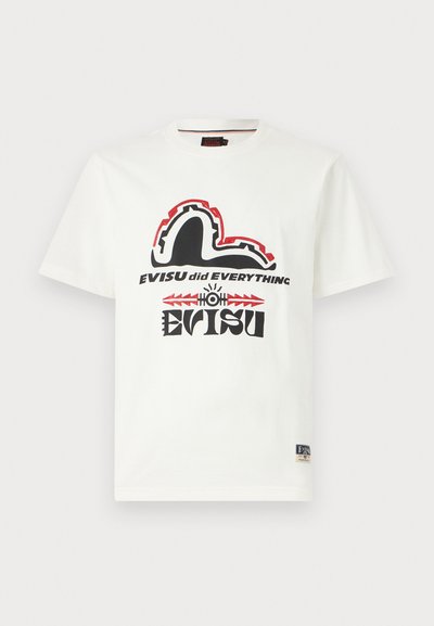 T-shirt en coton blanc avec un imprimé graphique noir et rouge, comprenant un texte stylisé et un design ressemblant à une vague ou à des falaises.
