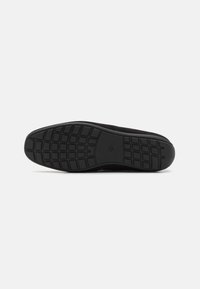 Semelle de chaussure en caoutchouc noir avec un motif en grille texturé pour une meilleure traction. Forme de orteil légèrement arrondie, bords lisses et talon renforcé.