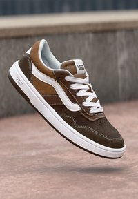 Bruna och beige mockasneakers med vita accenter, rund tå, plana snörning och signaturlogotyp på sidan och tungan. Texturerad ovandel och gummisula.
