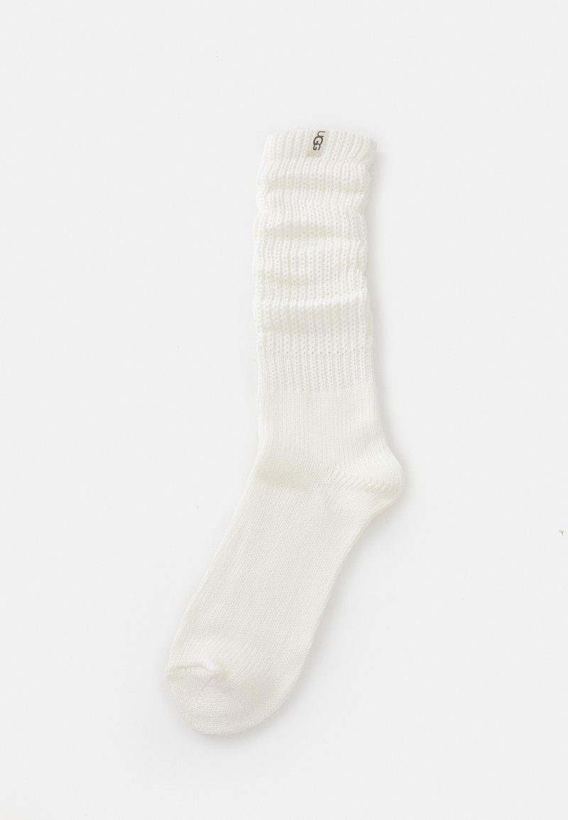White knitted socks with a gathered ribbed cuff, featuring a logo label on the side and smooth texture throughout the body.
