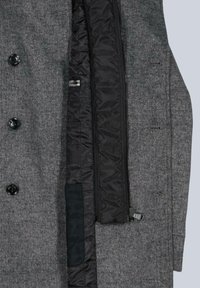 Grauer Mantel mit einer strukturierten Wollaußenseite und einem glatten schwarzen Futter. Verfügt über große schwarze Knöpfe, einen verdeckten Reißverschluss und eine Innentasche.