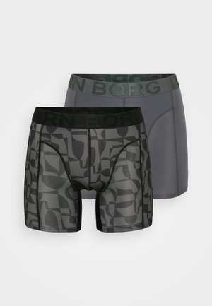 Dois pares de boxers para homem: um cinza e outro estampado em preto com formas abstratas. Ambos têm cintura elástica preta com texto.