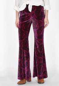 Fløjl flared bukser i dyb magenta med sort og lilla paisley mønster. Har en glat tekstur og en bred ben design.