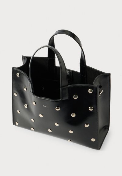Zwarte leren tote bag met ronde metalen studs, twee handvatten en een open ontwerp. Bevat een subtiel logo aan de voorkant.