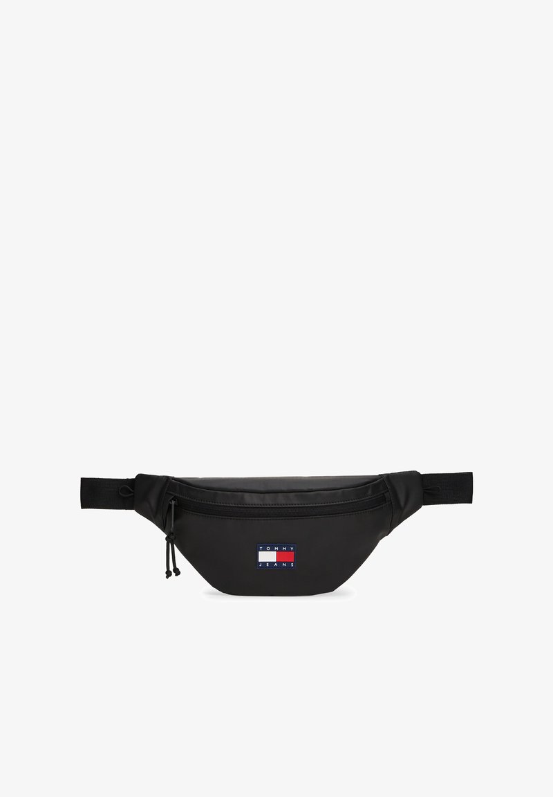 Fekete deréktáska sima felülettel. Elülső cipzáras zsebbel és piros, fehér, kék márkajelzéssel ellátott folttal. Állítható pánt.