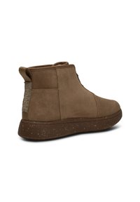 Bruine suede enkelboot met een gestructureerd achterpaneel, ronde neus en een gespikkelde rubberen zool. Voorzien van een aantrekhanger bij de hiel voor gemakkelijke bediening.