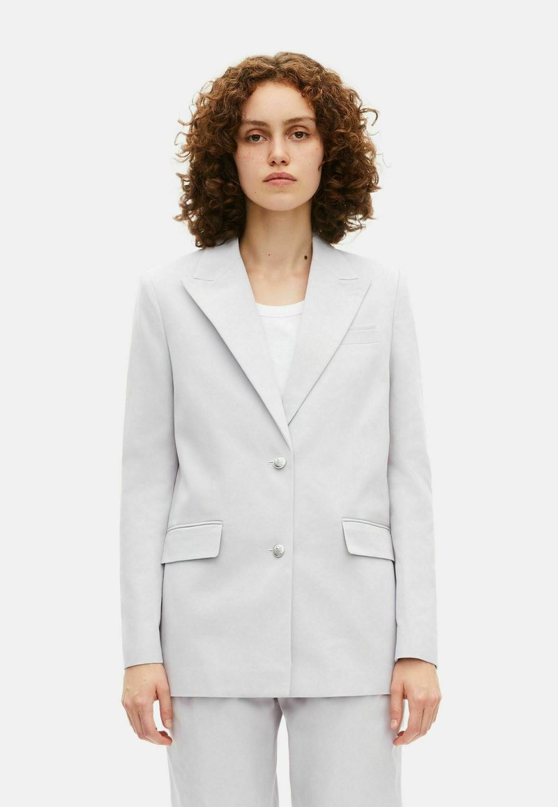 Blazer grigio chiaro realizzato in tessuto liscio, con revers a crestina, due tasche frontali e due bottoni rotondi per la chiusura.