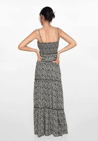 Maxiklänning i svart och vitt blommönster, med tunna axelremmar, en figurnära kropp och lagd volangkant. Lättviktig tyg med stretch.