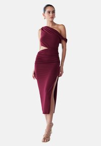 Burgundy off-shoulder mekko, jossa on laskostettua kangasta, leikkauksellinen yksityiskohta vyötäisyydessä, korkea sivuhelma ja kerätty pinta koko mekossa.