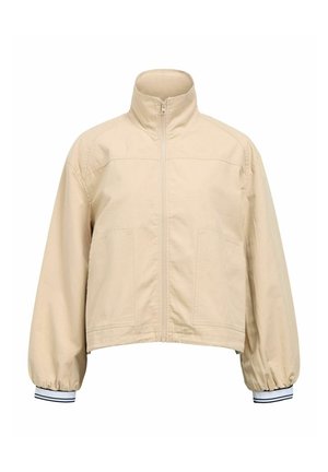 Chaqueta beige cortada con cuello alzado, cierre frontal de cremallera, dos bolsillos laterales y puños elásticos con franjas en azul marino y blanco.