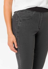 Graue Stretch-Jeans mit hoher Taille, Fronttaschen und einer glatten Textur, mit einem dezenten Glanz und einem elastischen Bund für zusätzlichen Komfort.