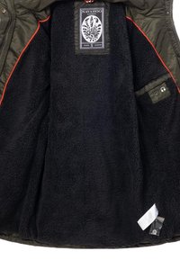 Zwarte fleece-gevoerde jas met een olijfgroene buitenkant, voorzien van een rond embleem-label, rode stiksels en een zak voor koptelefoons.