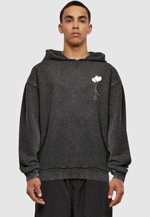 Svart bomullshettegenser med en oversized passform. Har et frontgrafikk av en person som holder tre ballonger. Teksturert stoff med ribbede mansjetter.