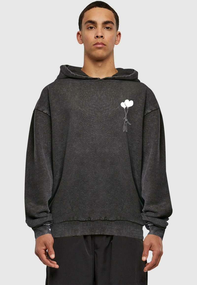 Sudadera de algodón negra con un corte oversize. Presenta un gráfico frontal de una persona sosteniendo tres globos. Tela texturizada con puños acanalados.