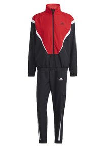 Tuta Adidas con un design rosso e nero, giacca con zip e colletto alto, e pantaloni neri con dettagli bianchi e tasca cargo.