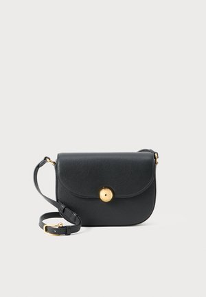 Borsa a tracolla in pelle nera con chiusura circolare dorata e tracolla regolabile su sfondo bianco semplice.