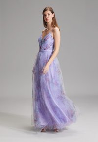 Lavendelfarbenes Abendkleid mit floralem Muster, durchscheinendem Overlay, V-Ausschnitt und verstellbaren Spaghetti-Trägern. Bodentiefer Stil, akzentuiert mit einem Gürtel.