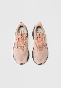 Pair of light pink athletic shoes with black soles and orange accents, viewed from above on a plain white background.