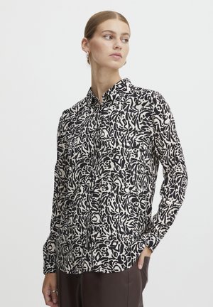 Long-sleeve button-up shirt in black and white abstract pattern, with a classic collar and two front pockets, made from lightweight fabric.