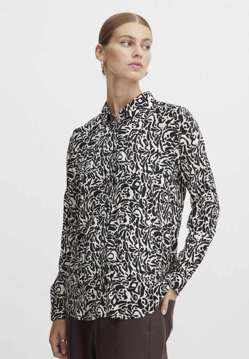 Long-sleeve button-up shirt in black and white abstract pattern, with a classic collar and two front pockets, made from lightweight fabric.