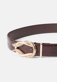 Burgundy bælte lavet af tekstureret kunstlæder med en guldfarvet slangeformet spænde og et elegant design, der har justerbare hak.