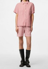 Červeno-bílý pruhovaný tričko s krátkým rukávem a odpovídající šortky, vyrobené z lehké tkaniny, doplněné vysokými černými botami až ke kolenům.