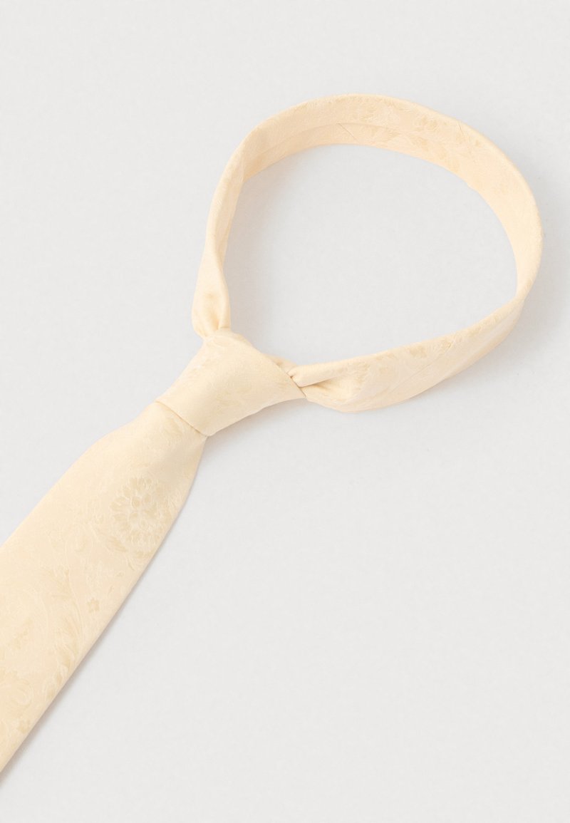 Ljust gul slips med ett subtilt blommönster, tillverkad av slät tyg. Har en klassisk smal form och en standardknut.