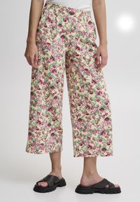 Pantalons larges à motif floral en crème, ornés de motifs roses, violets et verts. Confectionnés en tissu léger, avec une coupe décontractée et une longueur cropped.