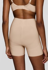 Shorts modellanti beige con pannelli testurizzati e una finitura liscia, dotati di vita media e design senza cuciture per una vestibilità confortevole.