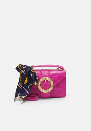 Petit sac à main rose vif avec texture crocodile, une grande boucle ronde décorative avec des perles et des cristaux, et un foulard noir à motifs noué.