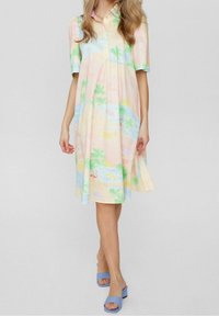 Robe à manches courtes aux couleurs pastel avec un motif de palmiers et de plage, dotée d'un col et d'une coupe ample. Associée à des sandales à talons blocs bleu clair.