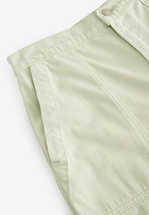 Svijetlozelene hlače od rebrastog materijala imaju zatvaranje na dugme i šivane detalje. Dizajn uključuje bočne nabore za dodatnu teksturu.