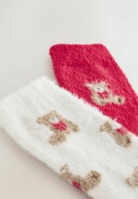 Punase ja valge karvased sokid, millel on karupoegade muster. Valgel sokil on pehme tekstuur, millel on pruunid karud ja punased aktsendid.