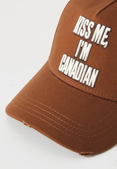 Casquette de baseball marron avec un texte brodé blanc "KISS ME, I'M CANADIAN." Présente une visière incurvée et des détails cousus.