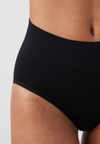 High-waisted black stretch panties made of smooth fabric, featuring a seamless design with a soft waistband and no visible seams.