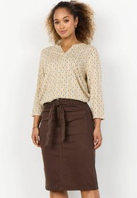 Beige kuvioitu pusero, jossa on Three-quarter hihat, yhdistetty ruskeaan korkeavyötäröiseen kynähameseen, jossa on solmittava vyö ja etutaskut.