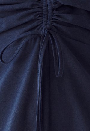 Tessuto navy con dettagli arricciati e corde regolabili, creando pieghe testurizzate. Superficie liscia con una finitura morbida.