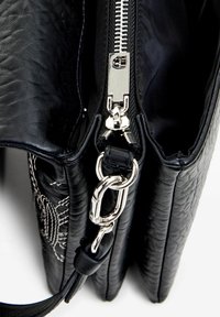 Black leather bag with a textured finish, silver zipper, and hardware. Interior visible, featuring two compartments and a detachable strap.